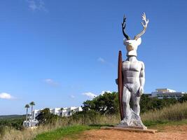 Statue of a man with a deer head and a surfboard in front of the Atlantic Ocean in the city of Nazare photo