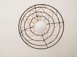 Stylish modern ceiling lamp with a unique woven design. The black wire frame and beige accents create a striking visual. photo