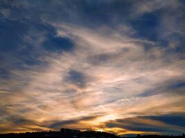 Dramatic sunset sky with layered clouds and silhouetted hills. photo