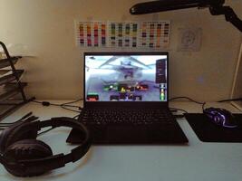 Gaming setup Laptop displaying a game, gaming headset, mouse, and color swatches on a desk. Ideal for articles about gaming, technology, or creative hobbies. photo