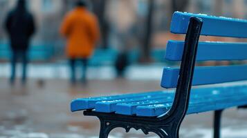 Snowy Winter Day Blue Park Bench with Blurred Background of People photo