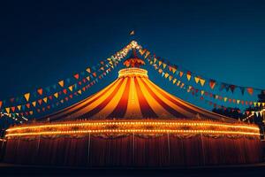 Large circus tent illuminated at night with colorful flags. photo