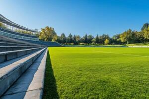 Empty stadium with green grass and concrete bleachers on sunny day photo