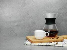 Coffee in a glass jug and cup on tray on stone texture background. photo
