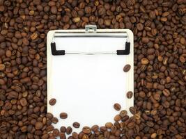 Board on coffee beans texture background. Paper for notes. Top view. photo