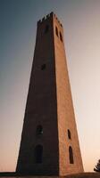 A minimalist composition captures the silhouette of an ancient tower against a gradient sky, with open areas of negative space. photo