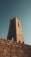 The silhouette of an ancient tower is set against a gradient sky in a minimalist vertical composition with wide open space. photo