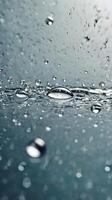 A close-up vertical image of glass with water droplets, set against a defocused background ideal for text placement. photo
