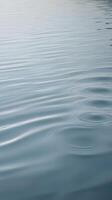 A tranquil vertical image showcasing subtle ripples on calm water, with clear areas for text placement. photo