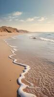 A vertical scene of a serene seashore, where gentle waves caress the sandy shore, framed by soft pastel hues and an open sky for text space. photo