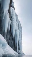 A vertical composition of a stunning icy cliff with intricate ice patterns, set against a vast sky providing room for text overlay. photo