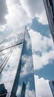A detailed vertical shot of a modern glass building, reflecting soft clouds in its surface, leaving plenty of empty space for text. photo