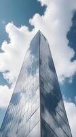 A high-detail vertical shot of a modern glass skyscraper reflecting soft clouds, with plenty of negative space. photo