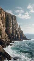 A peaceful vertical image of towering sea cliffs, with gentle waves at the bottom and a clear sky for design use. photo