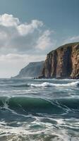 A calm vertical view of towering cliffs by the sea, with subtle waves at the base and empty sky space for design purposes. photo