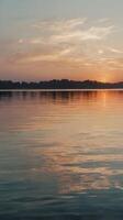 A vertical image of soft sunset colors mirrored on calm water, creating a peaceful ambiance with space for text. photo