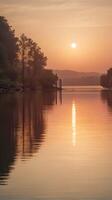 A vertical photo of soft sunset hues reflecting on still water, creating a calm atmosphere with copy space.