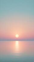 A tranquil vertical background of a pastel-colored sunrise over a quiet horizon, with blank space for text or designs. photo
