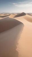 A high-detail vertical view of wind-swept sand dunes with smooth contours and an open sky for copy placement. photo