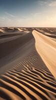 Vertical composition of smooth sand dunes with wind-blown ridges, a minimal color palette, and expansive sky for copy space. photo