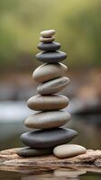 A vertical stack of smooth river stones against a blurred natural background, with ample blank areas for copy. photo