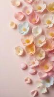 A soft-focus vertical composition of pastel flower petals, arranged with space on the edges for text overlay. photo