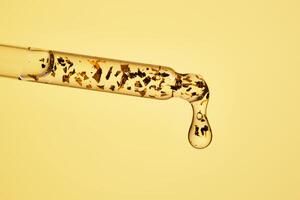 24 k gold facial serum in a pipette on a yellow background. photo