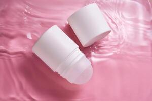 Roll-on deodorant on a pink background in clear water. photo
