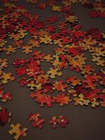 Orange Puzzle pieces scattered on brown surface, creating intriguing pattern photo