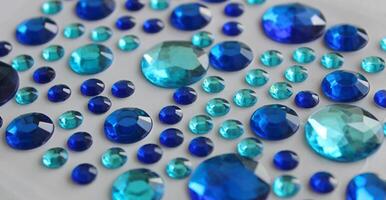 Different Size And Blue Shades Faceted Crystals On White Surface Closeup Angle View photo