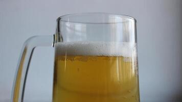 Top part of glass with handle filled of craft brown ale covered with foam closeup view photo
