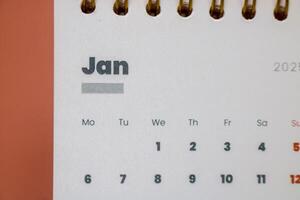 Close up of January month of the beginning of the year 2025 in the 2025 calendar in pink isolated on a pink background. Calendar and Note Pad Happy New year 2025. photo