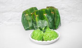 Green sticky rice tape shaped into a circle served on a plate isolated on a white background. Indonesian sticky rice tape wrapped in banana leaves photo