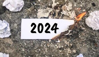 Paper burning on fire and pile of paper waste with 2024 written on it. new life and new year 2025 concept. 2024 paper is burning, say goodbye to 2024 photo