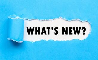 Words whats new on white background and torn blue paper. Whats new. The concept of finding fresh informatio photo