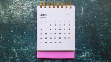 Close up of January 2025 in the pink 2025 calendar on the table. Calendar and Note Pad Happy New Year 2025. Zoomed in first of January 2025 in the calendar photo