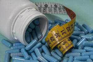 bottle of pills, some of which spilled a light blue surface photo