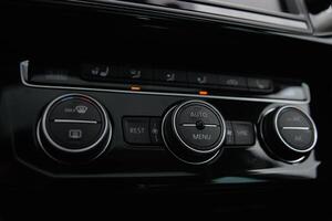 Modern car climate control panel with buttons and dials for temperature fan speed and AC photo