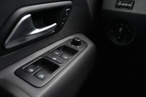 Close up of car door panel with window controls and door handle photo