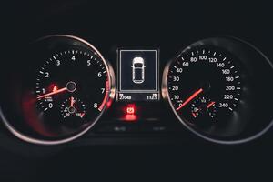 Close up of a car's dashboard at night showing the speedometer tachometer and digital display photo