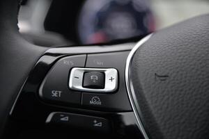 Close up of a car's steering wheel controls featuring buttons for cruise control mode selection and settings adjustments photo