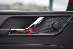Close up of a car's interior door panel showcasing the door handle and mirror controls photo
