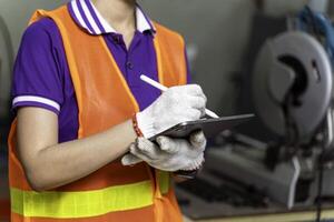 Closeup and crop hands of industrial engineer checking of work on tablet at industrial workshop. photo
