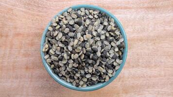Flat Lay of Split Black Gram Black Lentil, Urad Dal, Vigna Mungo in a Bowl on Neutral Wooden Background photo