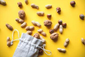 Top view on hazelnuts and peanuts in a cloth bag on a yellow background photo