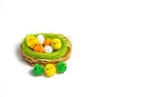 A basket with a bunch of colorful eggs and a few chicks photo