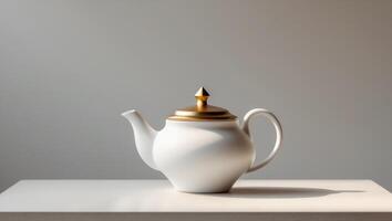 A white tea pot with a gold lid sits on a tableA white tea pot with a gold lid sits on a table. photo