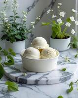 Ice cream tub with scoops set on a marble table surrounded by plants for dessert concept photo