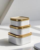 three white tins with gold lids stacked on top of each other photo