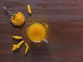 Herbal tea with turmeric powder and turmeric roots on a table photo